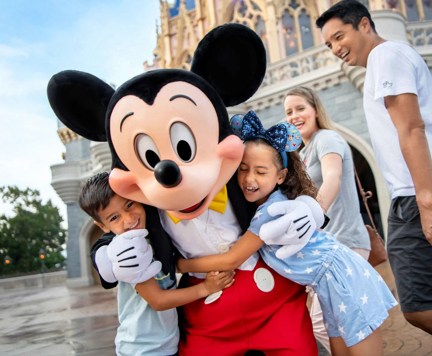 Dos niños disfrutando frente al castillo de Magic Kingdom junto a Mickey Mouse